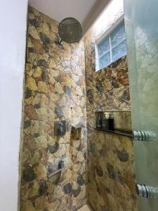 a bathroom with a shower with a stone wall at Montani Beach Resort Puerto Galera powered by Cocotel in Puerto Galera