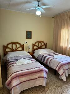 a bedroom with two beds and a ceiling fan at Apartamentos Congo in El Campello