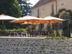 an outdoor patio with tables and chairs with umbrellas at Les Deux Ponts in Pierre-Perthuis