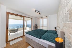 een slaapkamer met een bed en een balkon met uitzicht op de oceaan bij Luxury beachfront villa in Kožino, Zadar with stunning sea views in Kožino