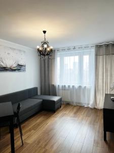 a living room with a couch and a chandelier at Coser Apartamenty ONZ in Warsaw