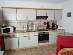 a kitchen with white cabinets and a sink and a microwave at Ferienwohnung Eulenhof in Templin