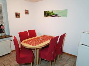 a dining room with a table and red chairs at Ferienwohnung Eulenhof in Templin