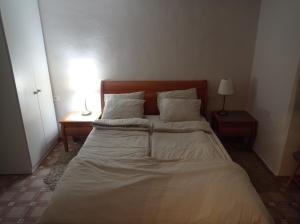a bed with white sheets and pillows in a bedroom at הפינה היפה ליד החומות in Jerusalem