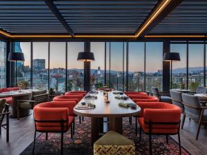 een restaurant met tafels en stoelen en grote ramen bij Swissôtel Tbilisi in Tbilisi City