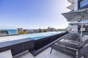 a swimming pool on the roof of a building with chairs at 102 Aurum Residences by Totalstay in Cape Town