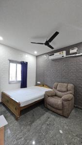 a bedroom with a bed and a couch and a ceiling fan at MR.WHITE PRIME RESIDENCY in Chennai