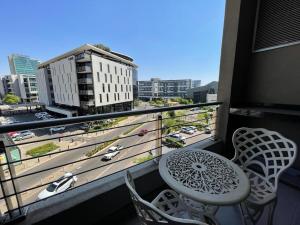 a balcony with a table and chairs and a view of a city at Luxe Menlyn Oasis in Pretoria