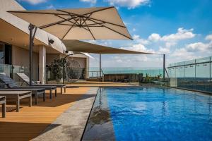 a swimming pool with an umbrella on a building at Luxe Menlyn Oasis in Pretoria