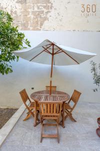 a wooden table and chairs with an umbrella at Stylish 3BR townhouse with Private Terrace & BBQ by 360 Estates in Paola