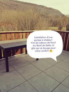 a wooden bench on a deck with a speech bubble at Au bord de Seille in Nevy-sur-Seille