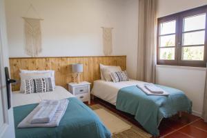 une chambre avec deux lits et une fenêtre dans l'établissement Quinta do Marmeleiro - Casa Marmeleiro, à Santiago do Cacém