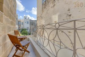 a balcony with two chairs and a wall at Stylish 3BR townhouse with Private Terrace & BBQ by 360 Estates in Paola