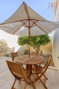 a wooden table and two chairs with an umbrella at Stylish 3BR townhouse with Private Terrace & BBQ by 360 Estates in Paola