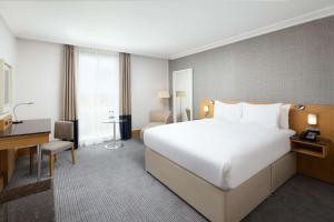 een hotelkamer met een groot bed en een bureau bij Hilton London Gatwick Airport in Horley +78 foto's