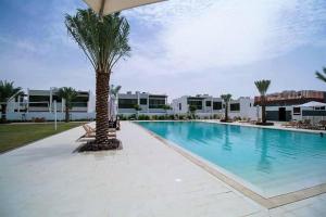 Experience Comfort in Our Charming 3-Bedroom Villa في دبي: مسبح بالنخيل بجانب مبنى