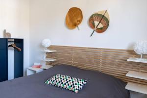 een slaapkamer met een bed met een kussen en hoeden aan de muur bij Le Mangin in Saint-Avold