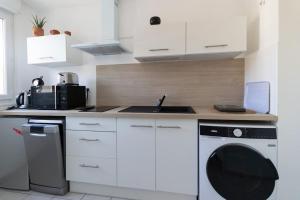 een witte keuken met een wasmachine en een wastafel bij Le Mangin in Saint-Avold