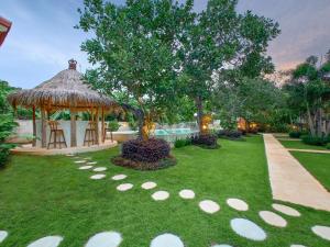 um jardim com um gazebo e uma árvore em Uluwatu Desa em Uluwatu