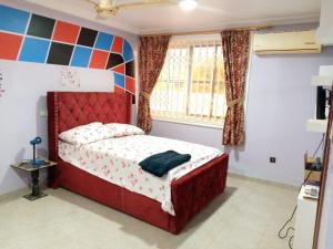 1 dormitorio con cama roja y ventana en SANAMOND VILLA, en Dodowa
