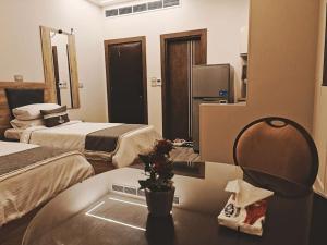 a hotel room with two beds and a desk with a table at Grand Room in Sheikh Zayed