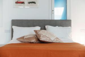 1 cama con 2 almohadas y manta naranja en Numero 11 Piazza Amendola - by MyHomeInComo, en Como