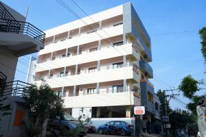 ein weißes Gebäude mit davor geparkt in der Unterkunft Alexa Service Appartments (1BHK,2BHK with Kitchen) in Tirupati