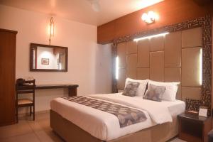 een slaapkamer met een bed, een bureau en een spiegel bij Hotel Old Urban Guest House in Kolhapur