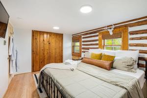 een groot bed in een kamer met een houten muur bij Modernized Log Cabin w Hot Tub Fire Pit & Views in Berkeley Springs