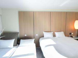 two beds in a hotel room with white pillows at Pullman Bordeaux Lac in Bordeaux