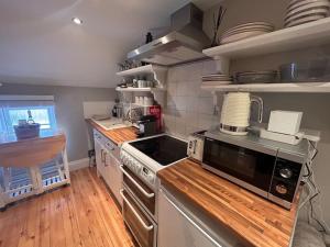 a kitchen with a stove and a microwave at The Gatehouse, Bijou studio apartment - sleeps 2 in Easingwold