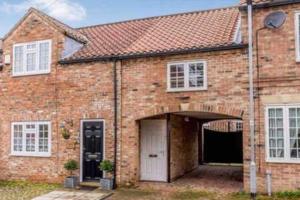 a brick house with a white door and a garage at The Gatehouse, Bijou studio apartment - sleeps 2 in Easingwold