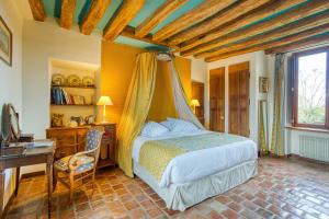a bedroom with a bed and a table and a desk at La Fauconnerie Du Roy in Montainville