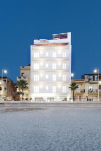 un edificio blanco con palmeras delante en Vuelle Residence Apartments, en Capo dʼOrlando