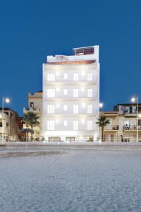 Un edificio blanco con palmeras delante. en Vuelle Residence Apartments, en Capo dʼOrlando
