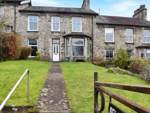 una vieja casa de ladrillo con césped delante en Belmont Apartment, en Arnside