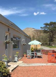 a patio with a table and an umbrella at Cosy Highland Cottage Tyndrum centrally located in Tyndrum