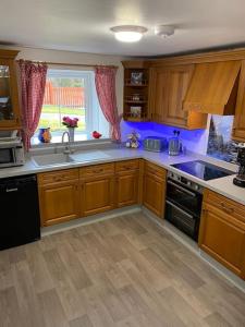 a kitchen with wooden cabinets and a sink and a window at Cosy Highland Cottage Tyndrum centrally located in Tyndrum