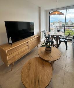 ein Wohnzimmer mit einem großen Flachbild-TV und Tischen in der Unterkunft nardos suites in Balcarce