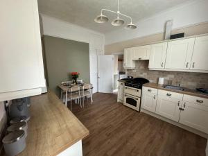 una cocina con armarios blancos y una mesa. en Ennerdale Edge - 4 Bed House en Cleator Moor