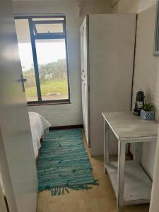 a room with a table and a window and a rug at Pondjiebotter in Pringle Bay