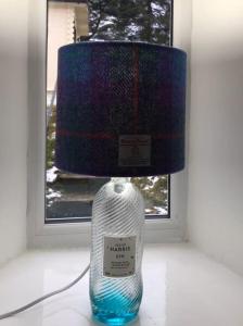 a lamp with a bottle sitting next to a window at Cosy Highland Cottage Tyndrum centrally located in Tyndrum