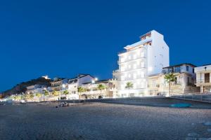 a white building on a beach with palm trees at Vuelle Residence Apartments in Capo dʼOrlando