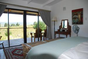 a bedroom with a bed and a view of a deck at Equleni Guest Farm in Sedgefield