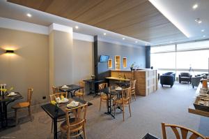 a restaurant with tables and chairs in a room at Cit'Hotel De Harlay in Compiègne