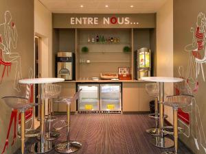 a kitchen with two tables and a counter with a refrigerator at ibis Issy les Moulineaux "Val de Seine" in Issy-les-Moulineaux