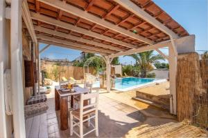 a patio with a wooden pergola and a table and a pool at Villa Hidden Gem Crete in Pangalochori