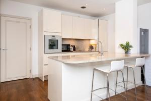 a kitchen with white cabinets and bar stools at Central 2 Bed Maissonette in London