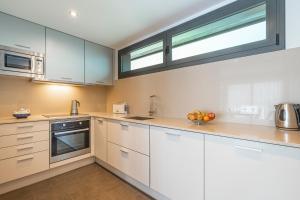 a kitchen with white cabinets and a window at Apartamento ático primera línea Playa Canyelles in Roses +14 photos