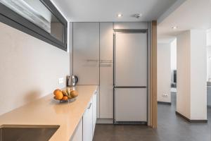 a kitchen with a refrigerator and a bowl of fruit on a counter at Apartamento ático primera línea Playa Canyelles in Roses